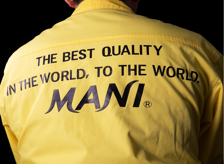 Back of a person wearing a yellow MANI jacket with the slogan 'THE BEST QUALITY IN THE WORLD, TO THE WORLD.