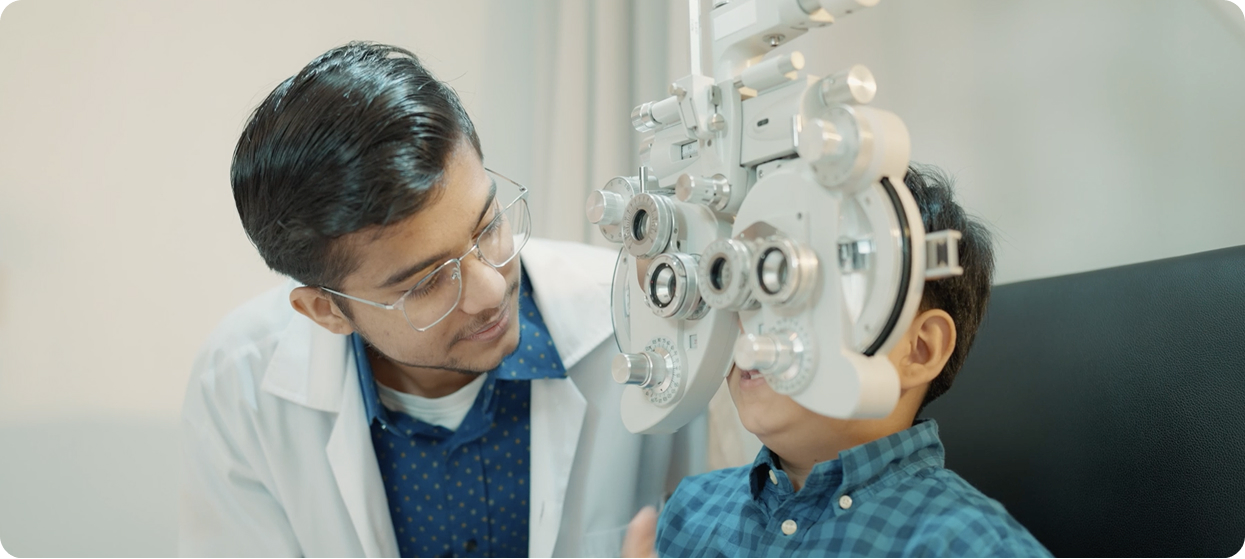 Optometrist conducting an eye examination for a young boy using a phoropter
