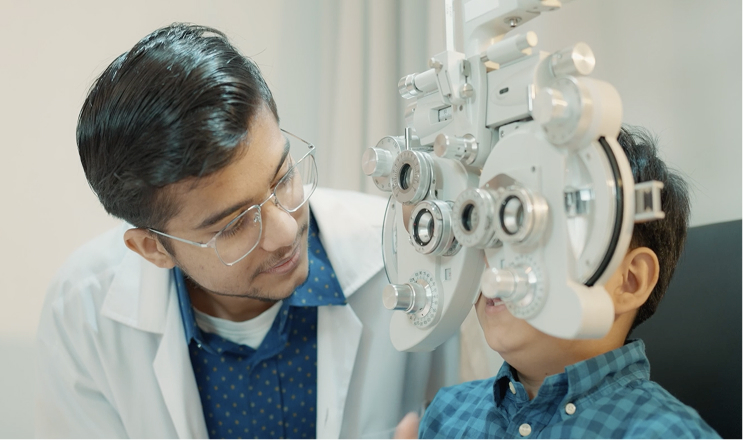 Optometrist conducting an eye examination for a young boy using a phoropter