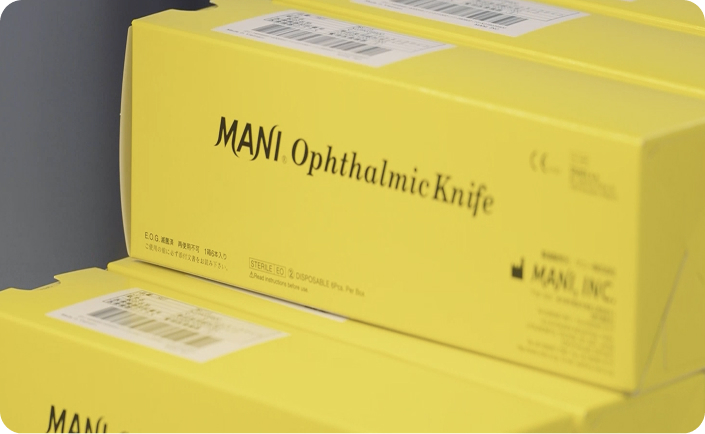 Close-up of yellow boxes labeled 'MANI Ophthalmic Knife' stacked on a shelf.