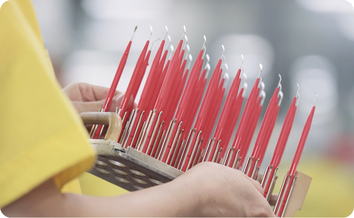 Close-up of a worker holding a tray of red-handled precision tools, possibly dental or surgical instruments.