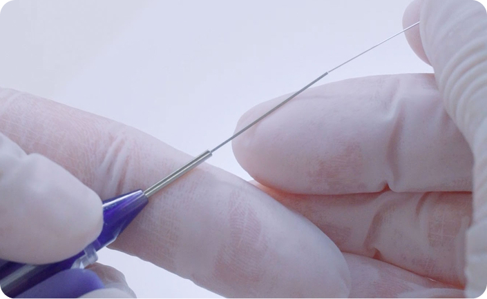 Close-up of gloved hands handling a thin medical device wire with precision