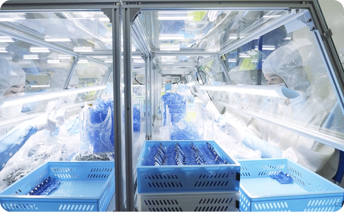Workers in cleanroom suits assembling medical or electronic components in a sterile production environment