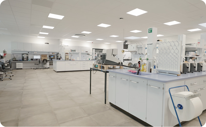 A spacious, well-lit laboratory with multiple workstations, scientific equipment, and white cabinetry
